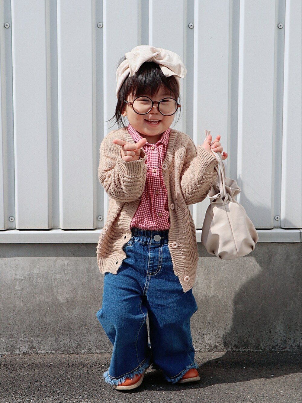 レッド系のシャツ/ブラウス、ベージュ系のカーディガン/ボレロ、ブルー系のデニムパンツを着用したキッズの春コーディネートの3枚目の写真