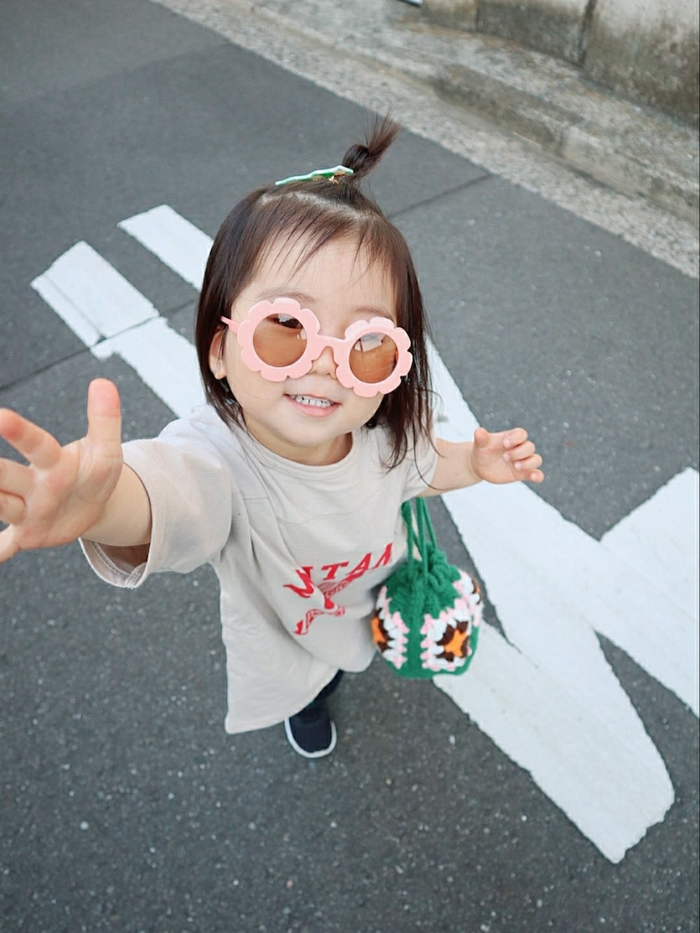 ベージュ系のワンピース、グリーン系のバッグ、ブラック系のスニーカーを着用したキッズの春コーディネートの5枚目の写真