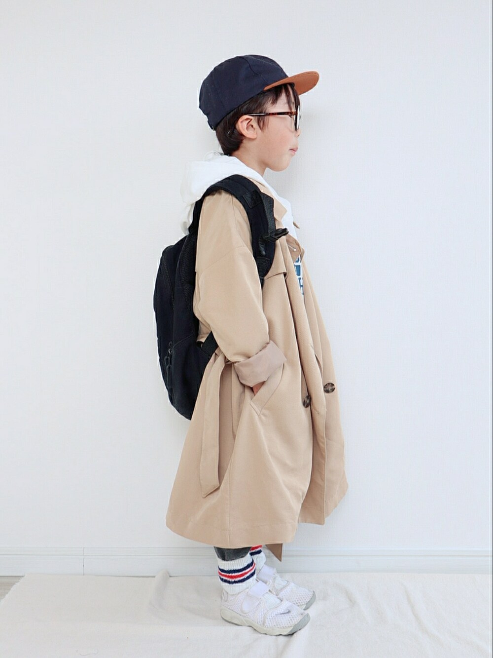 ベージュ系のトレンチコート、ホワイト系のパーカー、グレー系のスウェットパンツを着用したキッズの春コーディネートの2枚目の写真