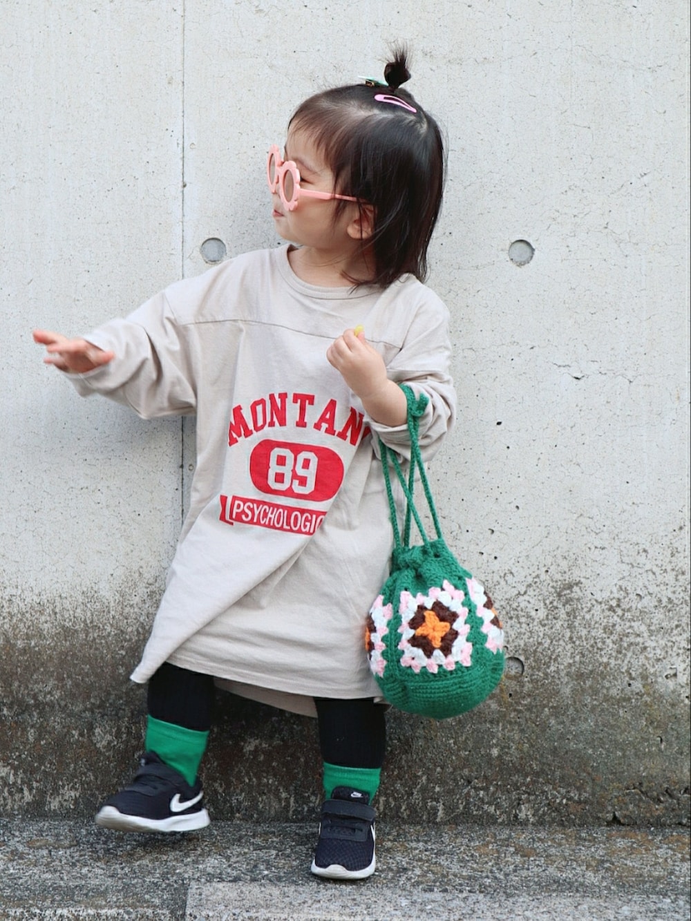 ベージュ系のワンピース、グリーン系のバッグ、ブラック系のスニーカーを着用したキッズの春コーディネートの2枚目の写真