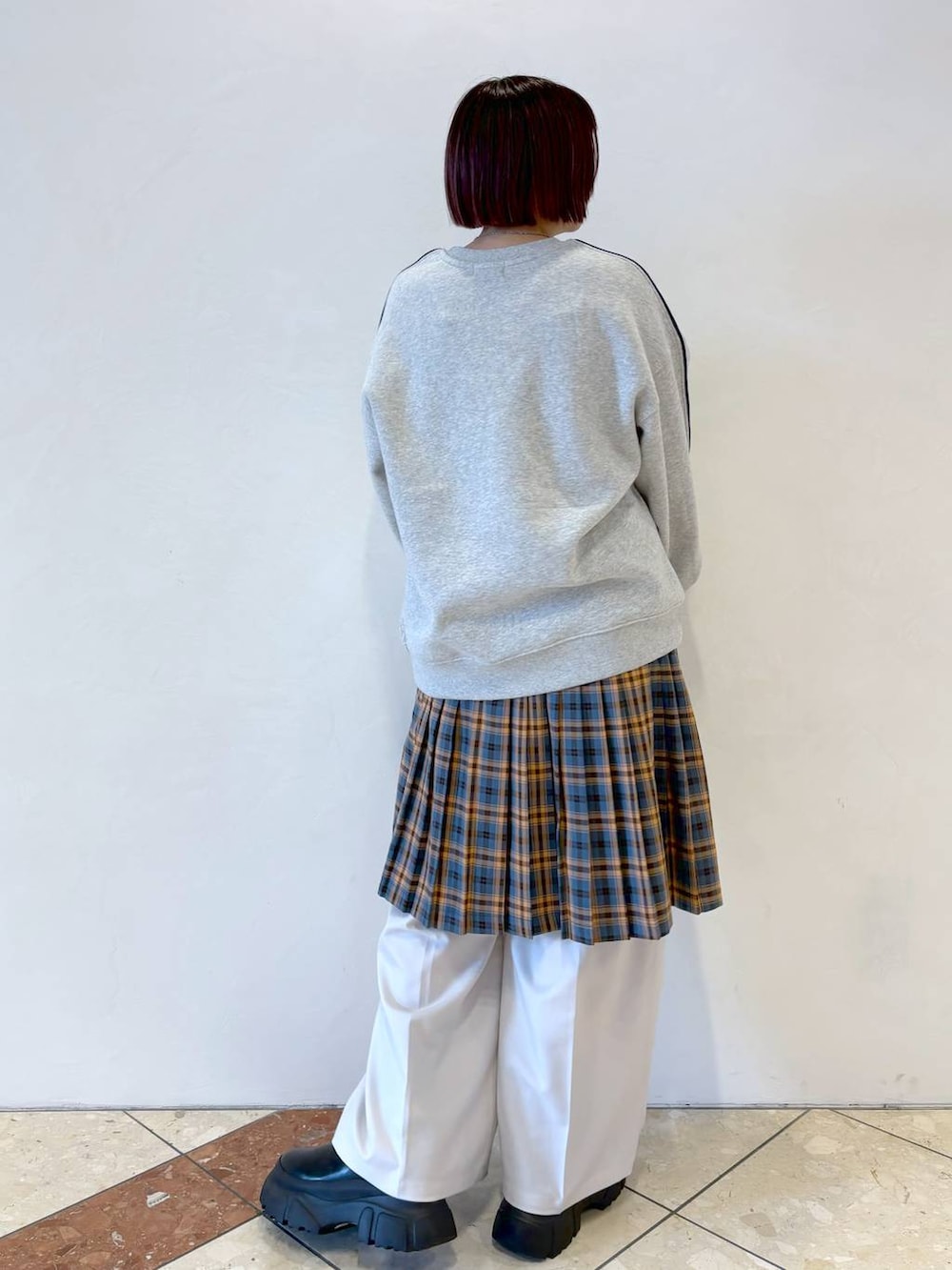 ベージュ系のスラックス、グレー系のスウェット、オレンジ系のスカートを着用したレディースの秋コーディネートの2枚目の写真