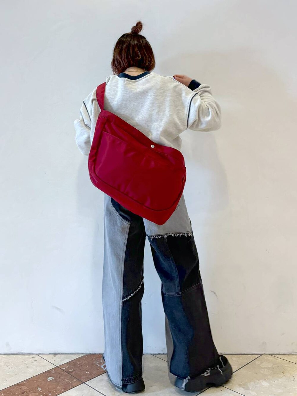 グレー系のスウェット、ブラック系のブーツ、レッド系のショルダーバッグを着用したレディースの冬コーディネートの3枚目の写真