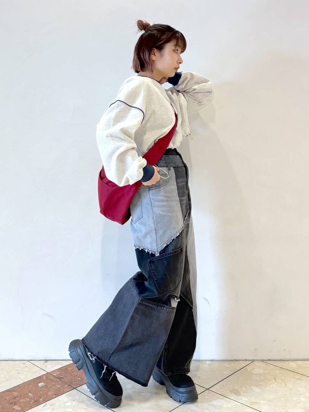 グレー系のスウェット、ブラック系のブーツ、レッド系のショルダーバッグを着用したレディースの冬コーディネートの2枚目の写真