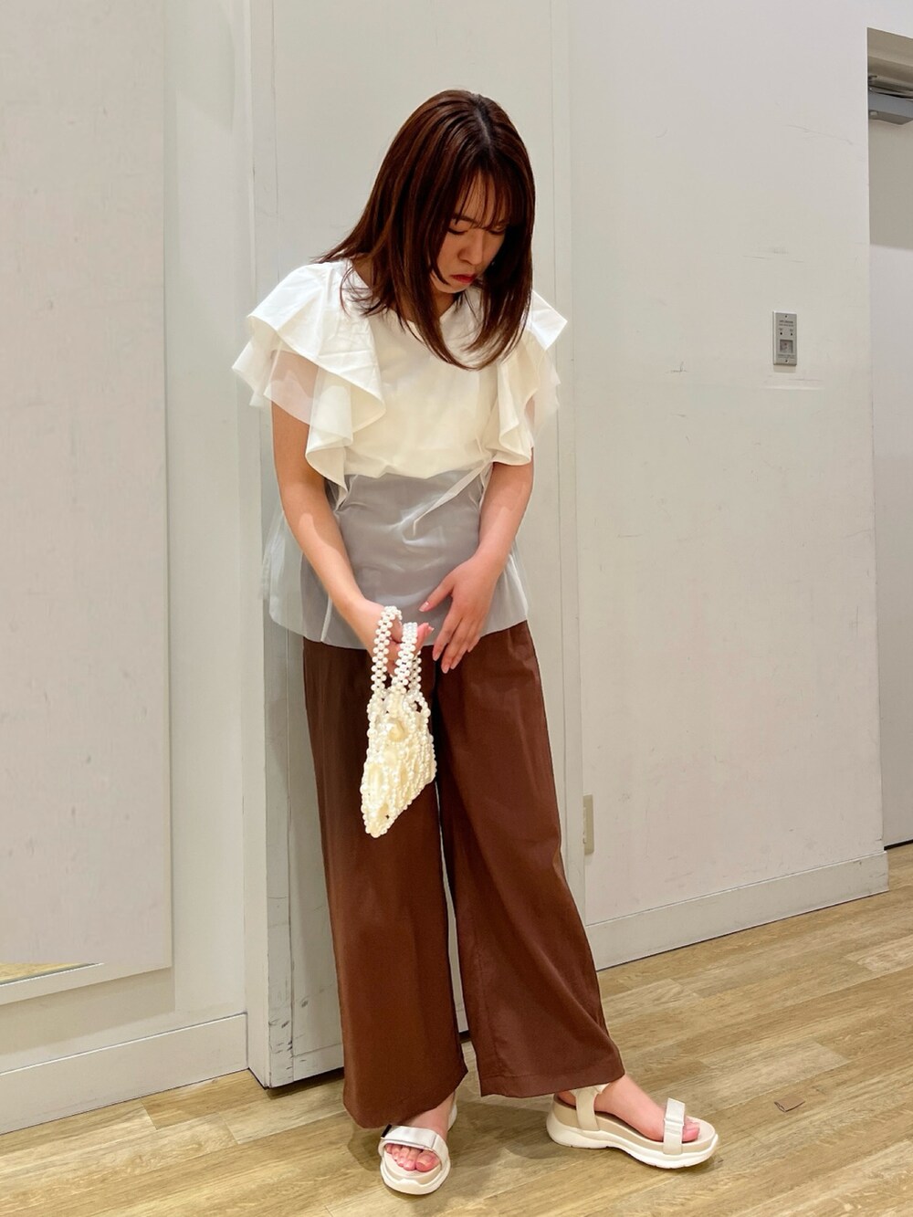 ホワイト系のサンダル、ホワイト系のTシャツ/カットソー、ホワイト系のハンドバッグを着用したレディースの春コーディネートの2枚目の写真