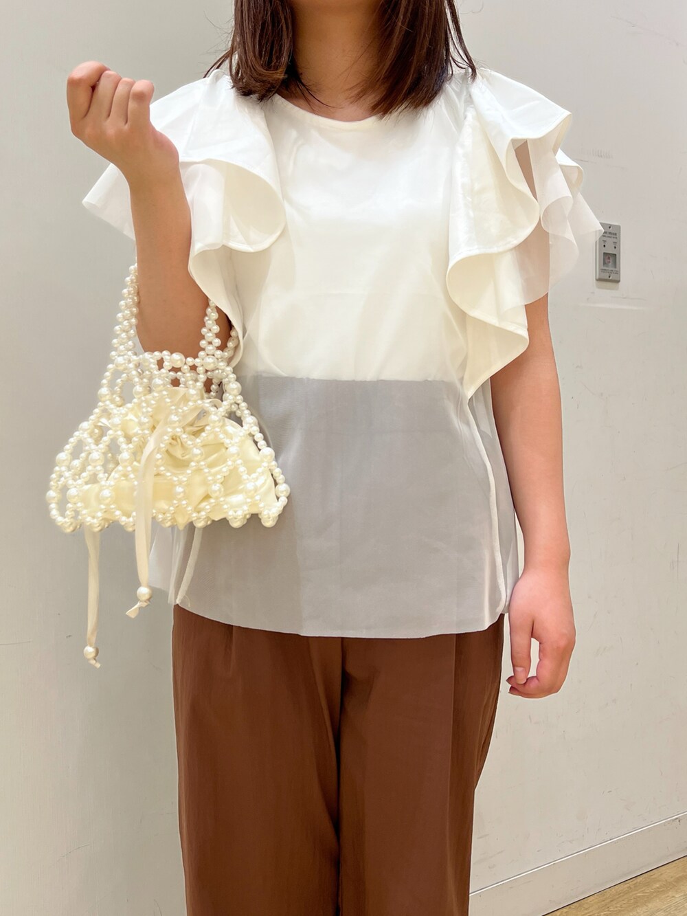 ホワイト系のサンダル、ホワイト系のTシャツ/カットソー、ホワイト系のハンドバッグを着用したレディースの春コーディネートの3枚目の写真