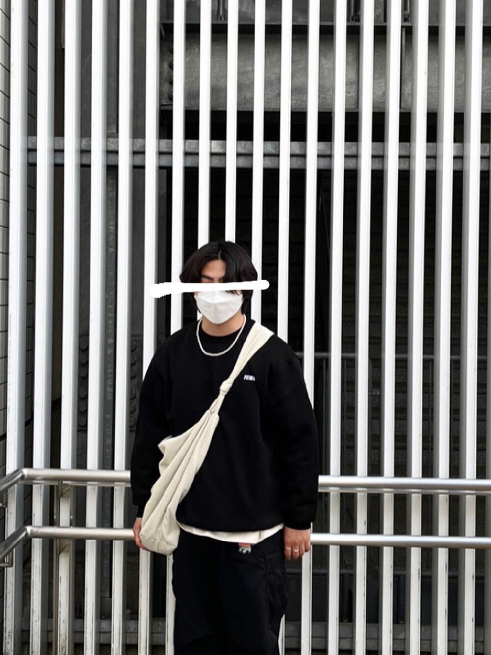 ブラック系のスウェット、ブラック系のスニーカー、ホワイト系のショルダーバッグを着用したメンズの春コーディネートの2枚目の写真