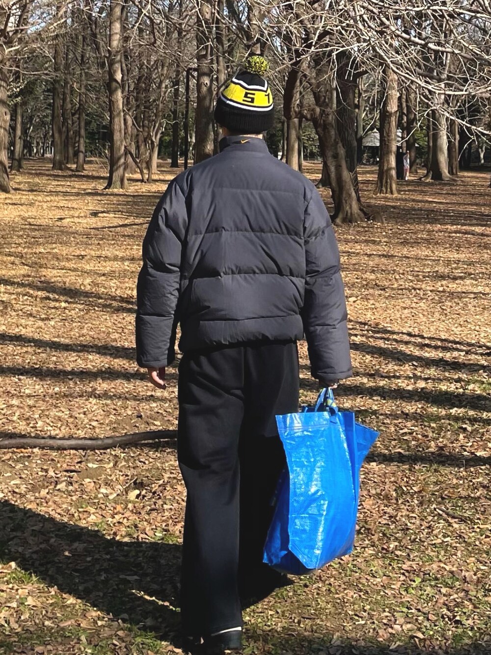 ブラック系のダウンジャケット/コート、ブラック系のスウェットパンツ、ブルー系のバッグを着用したメンズの冬コーディネートの2枚目の写真