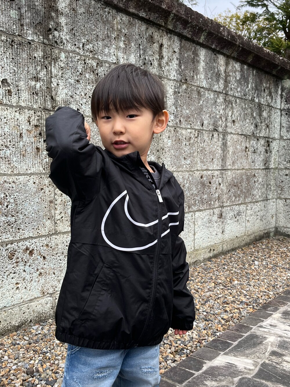 ブラック系のナイロンジャケット、ブルー系のパンツ、グレー系のスニーカーを着用したキッズの春コーディネートの3枚目の写真