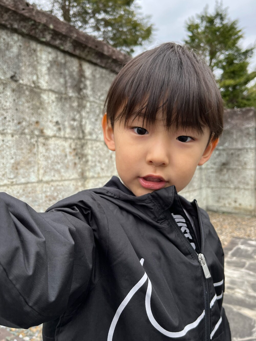 ブラック系のナイロンジャケット、ブルー系のパンツ、グレー系のスニーカーを着用したキッズの春コーディネートの2枚目の写真