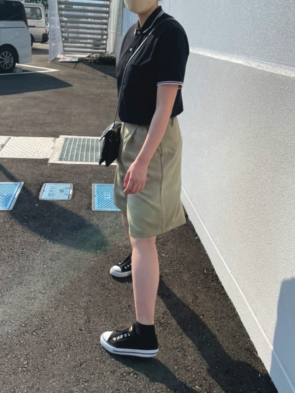 ブラック系のポロシャツ、グリーン系のパンツ、ブラック系のショルダーバッグを着用したレディースの春コーディネートの2枚目の写真