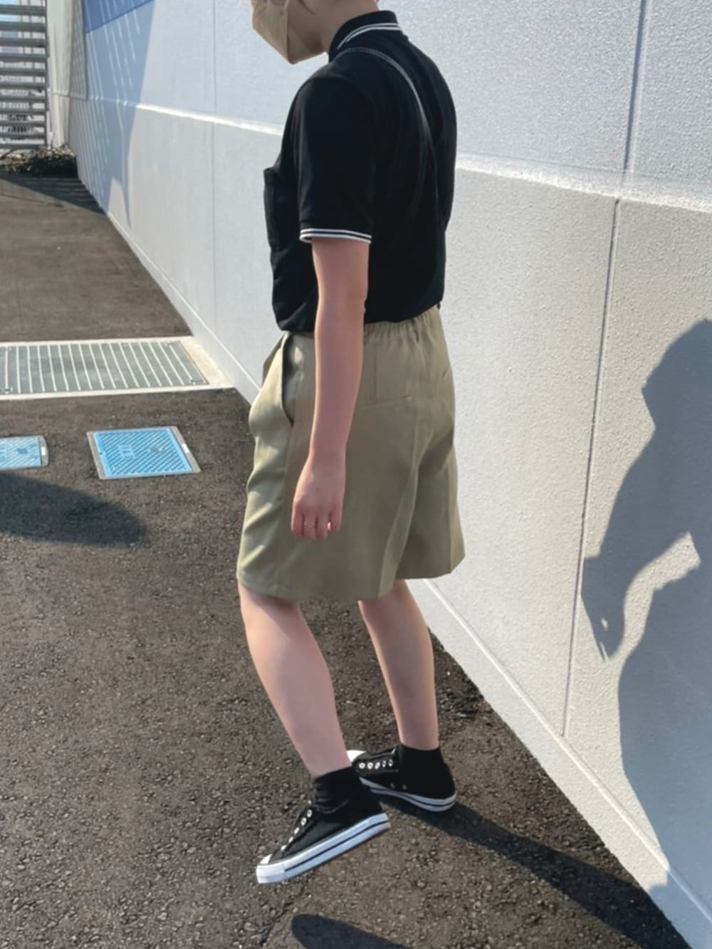 ブラック系のポロシャツ、グリーン系のパンツ、ブラック系のショルダーバッグを着用したレディースの春コーディネートの3枚目の写真