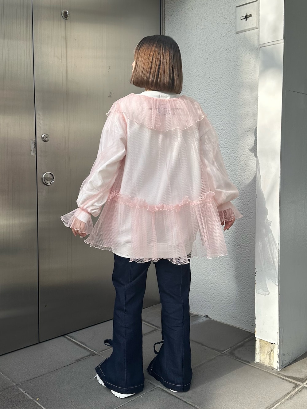 ホワイト系のスニーカー、ブルー系のデニムパンツ、ホワイト系のスウェットを着用したレディースの冬コーディネートの2枚目の写真