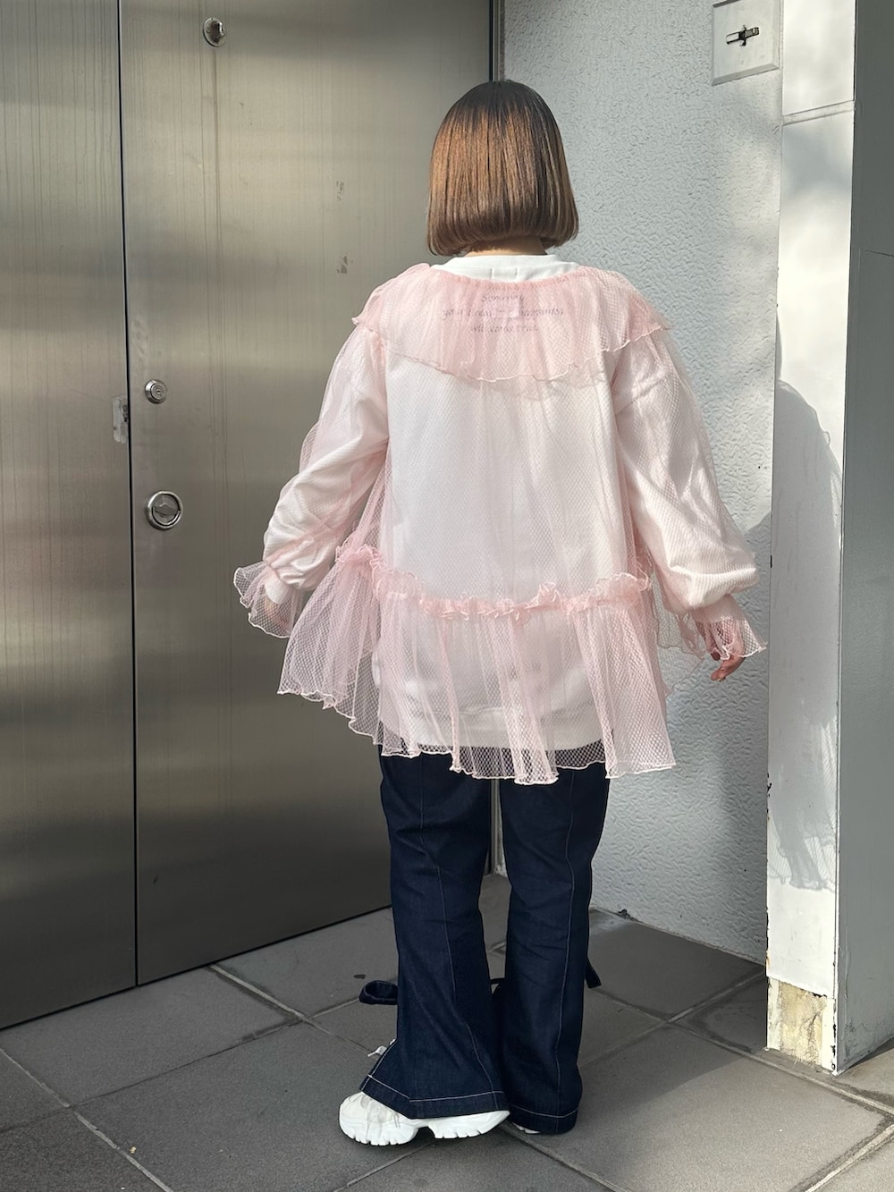 ホワイト系のスニーカー、ブルー系のデニムパンツ、ホワイト系のスウェットを着用したレディースの冬コーディネートの3枚目の写真