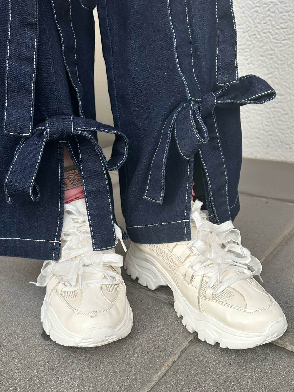 ホワイト系のスニーカー、ブルー系のデニムパンツ、ホワイト系のスウェットを着用したレディースの冬コーディネートの6枚目の写真