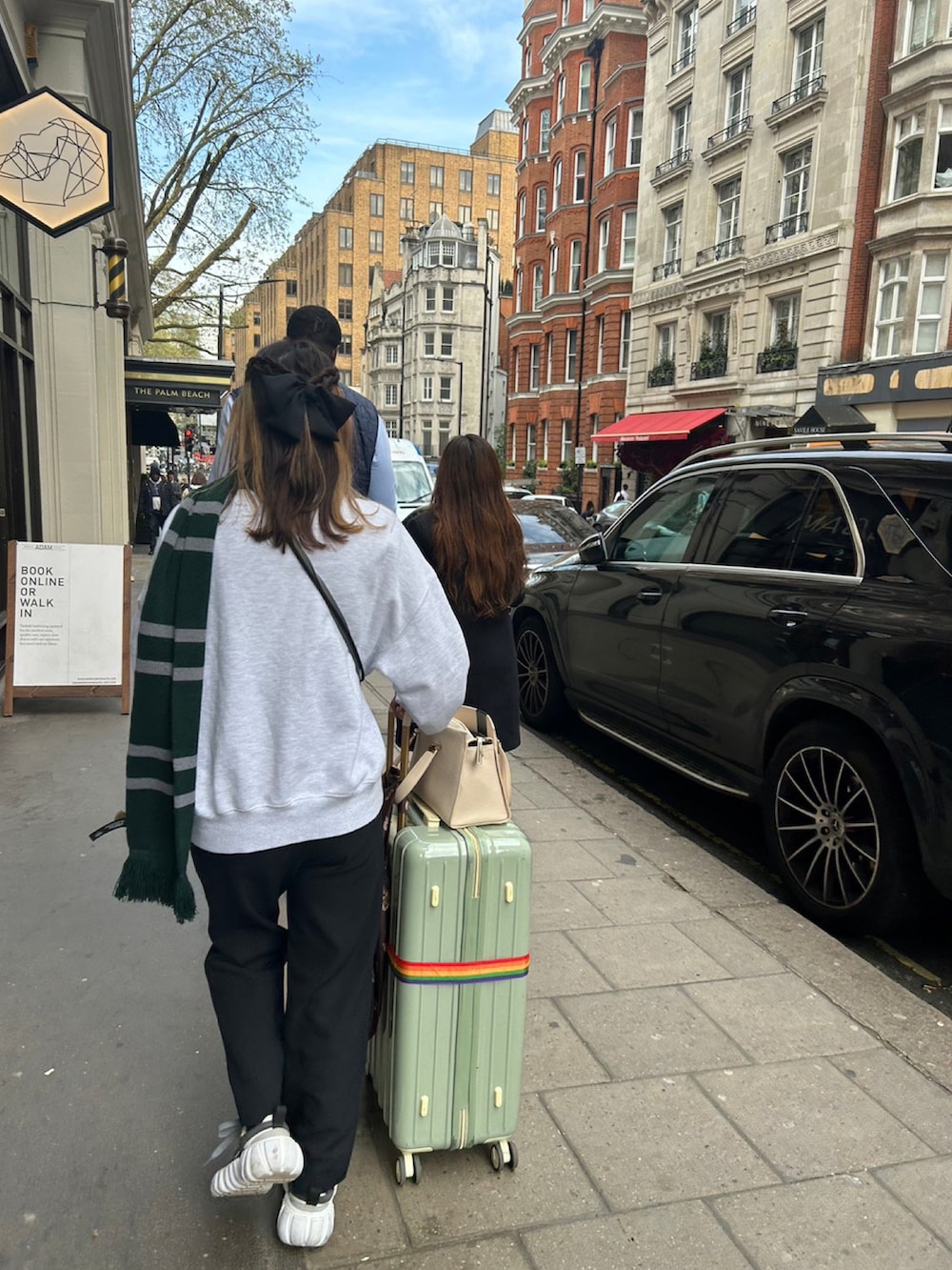 グレー系のスウェット、ホワイト系のスニーカー、ベージュ系のショルダーバッグを着用したレディースの夏コーディネートの2枚目の写真