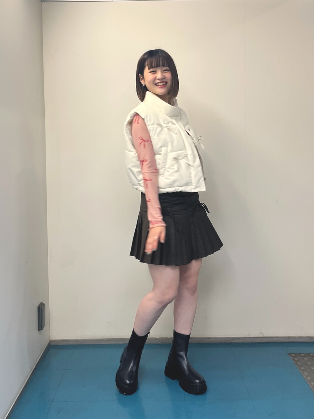 ブラウン系のスカート、ホワイト系のベスト、ピンク系のTシャツ/カットソーを着用したレディースの秋コーディネートの3枚目の写真