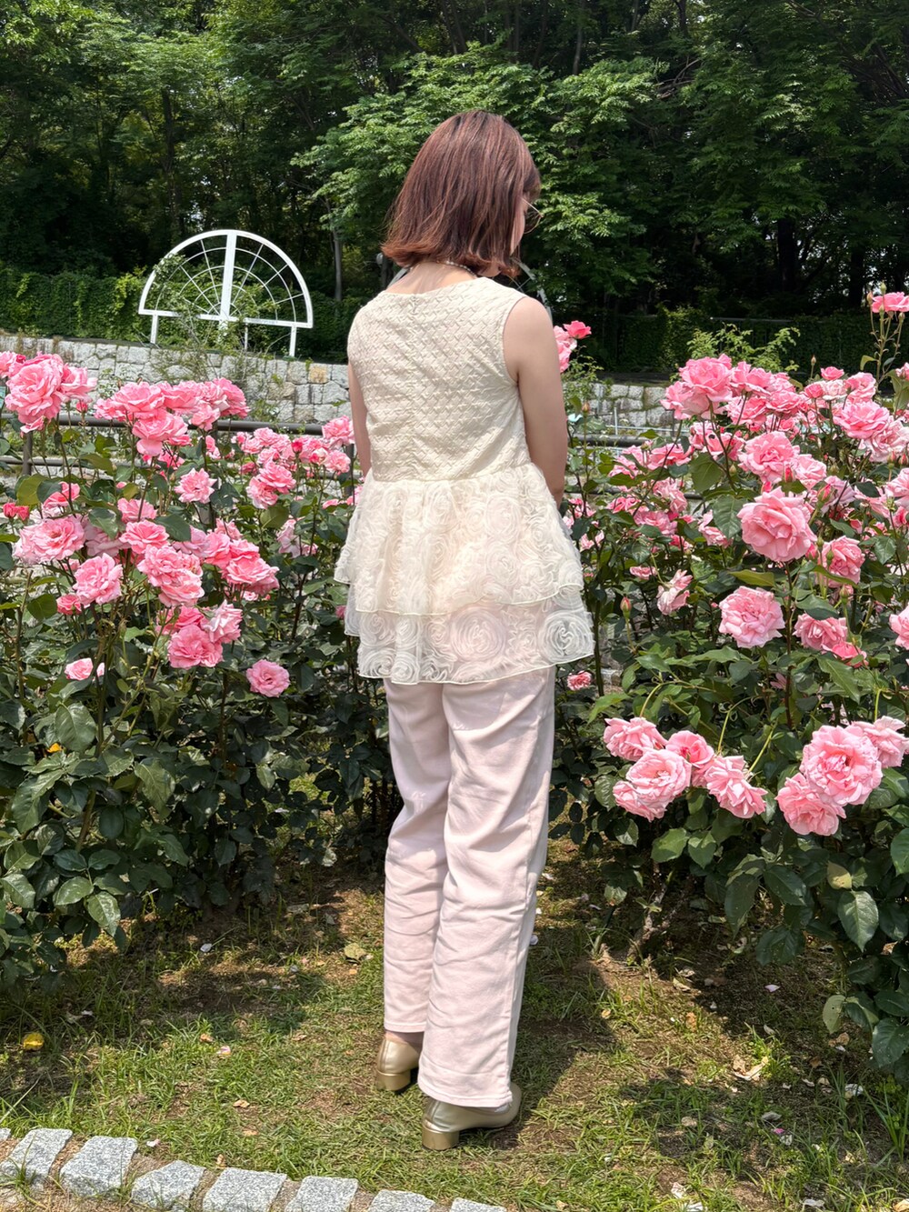 ピンク系のデニムパンツ、ベージュ系のチュニック、ゴールド系のパンプスを着用したレディースの夏コーディネートの3枚目の写真