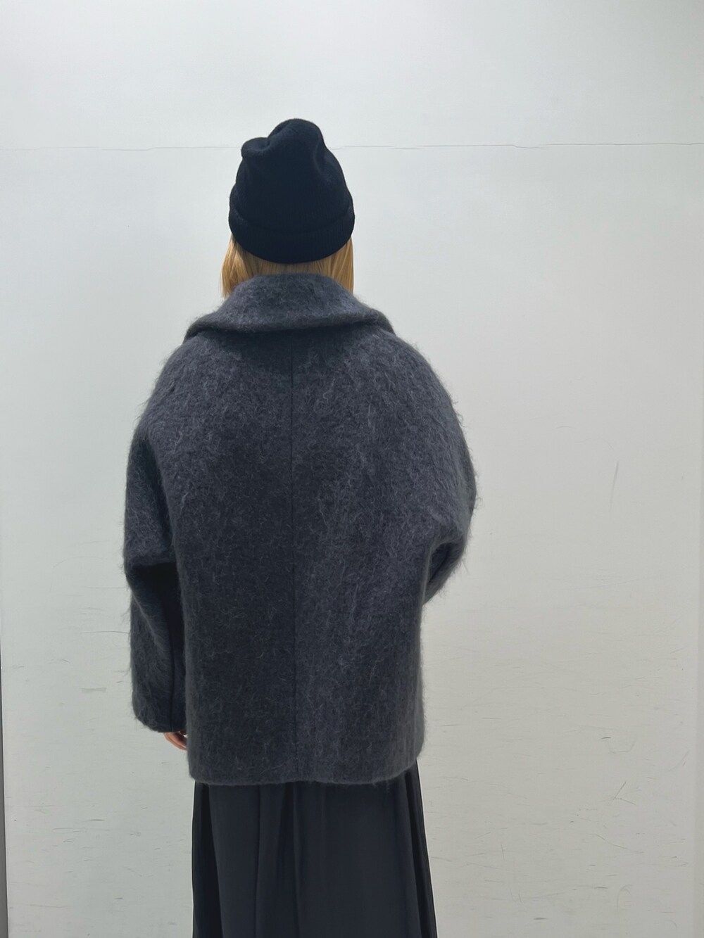 グレー系のピーコート、ブラック系のスカート、ブラック系のブーツを着用したレディースの秋コーディネートの5枚目の写真