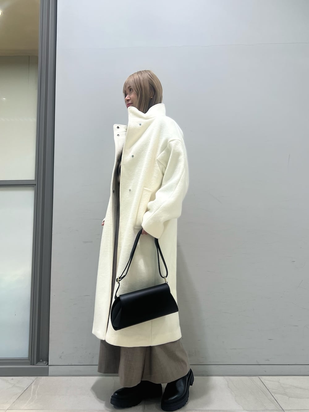 ブラック系のショルダーバッグ、ブラック系のブーツ、ホワイト系のその他アウターを着用したレディースの冬コーディネートの3枚目の写真