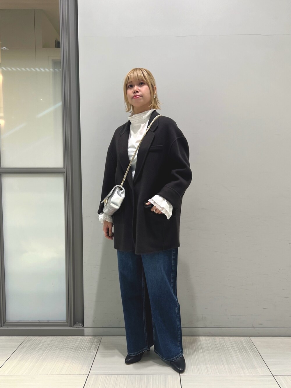 ブルー系のチェスターコート、ホワイト系のシャツ/ブラウス、ブルー系のデニムパンツを着用したレディースの秋コーディネートの2枚目の写真