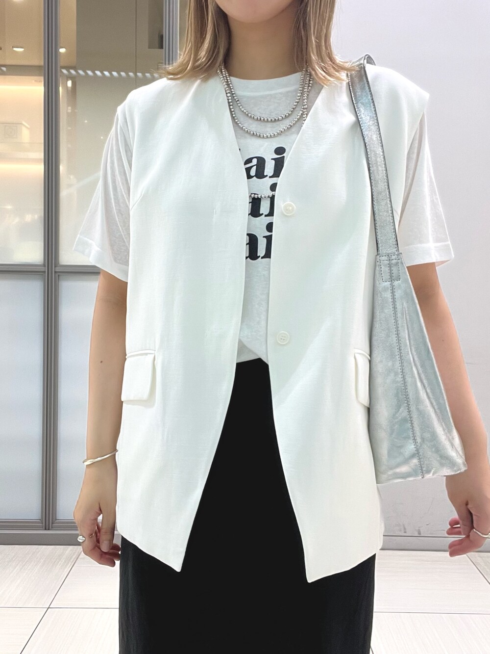 ホワイト系のベスト、ホワイト系のTシャツ/カットソー、ブラック系のスカートを着用したレディースの夏コーディネートの3枚目の写真