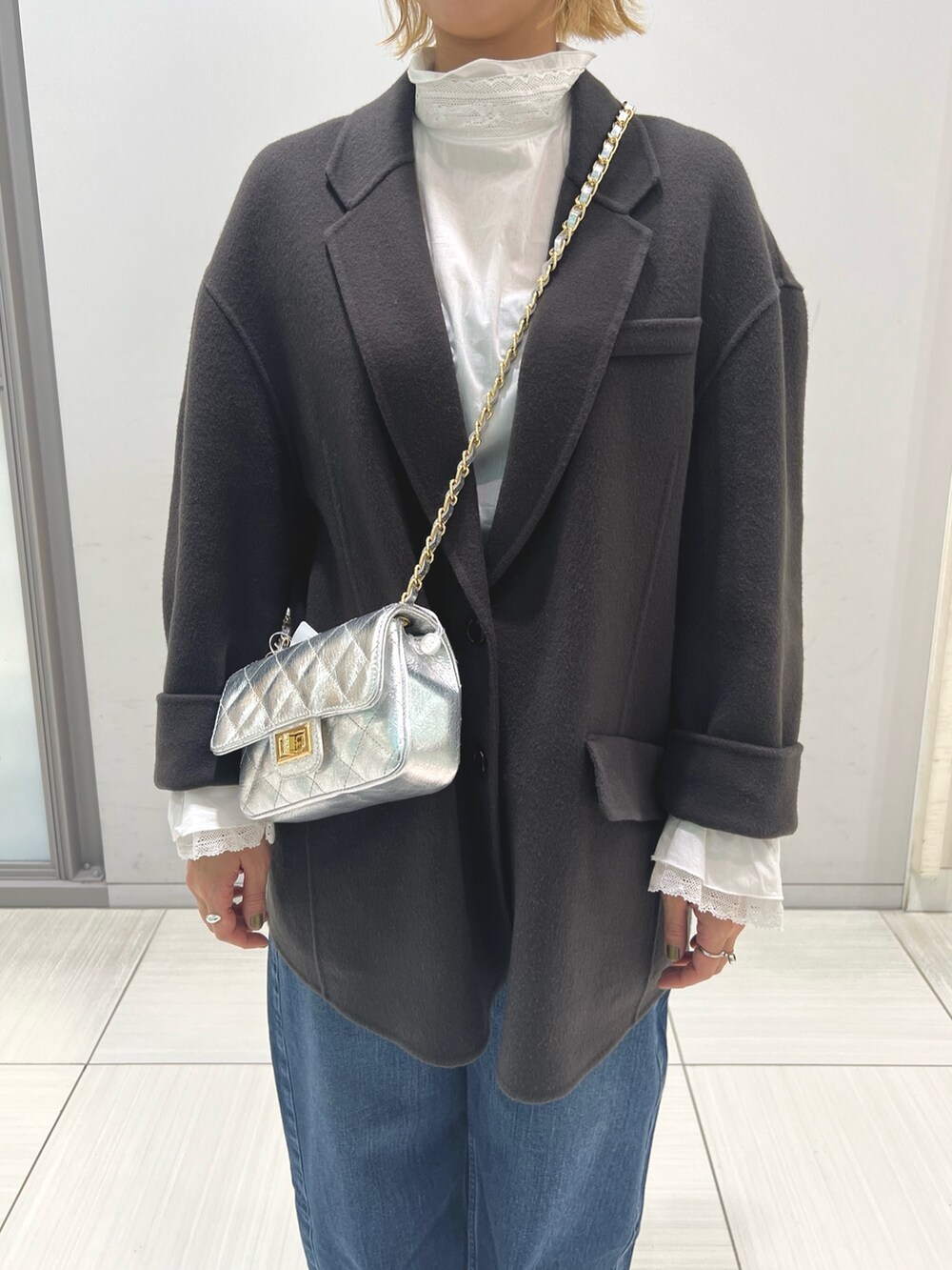 ブルー系のチェスターコート、ホワイト系のシャツ/ブラウス、ブルー系のデニムパンツを着用したレディースの秋コーディネートの4枚目の写真