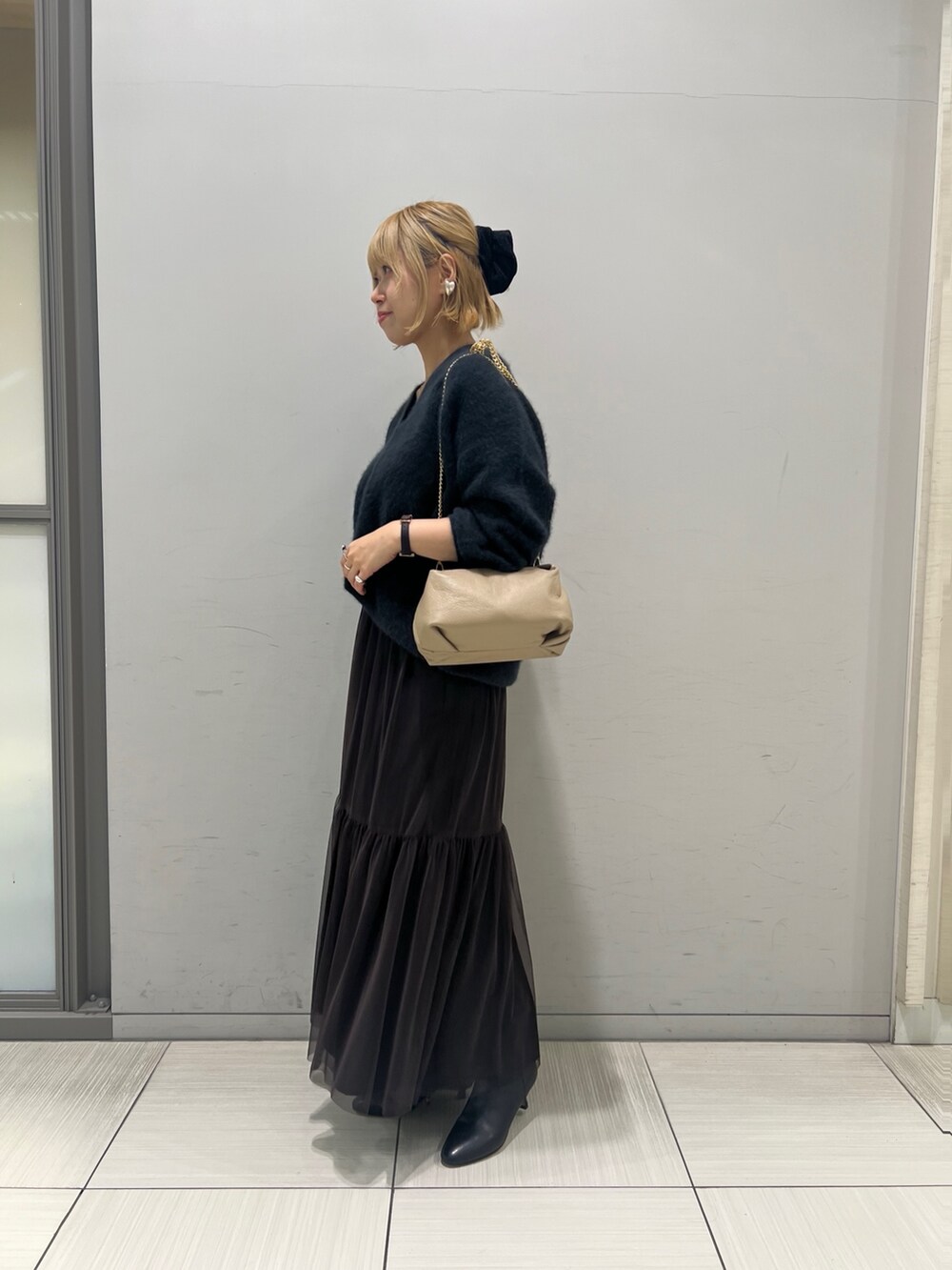 グレー系のニット/セーター、ブラウン系のスカート、ブラック系のブーツを着用したレディースの秋コーディネートの6枚目の写真