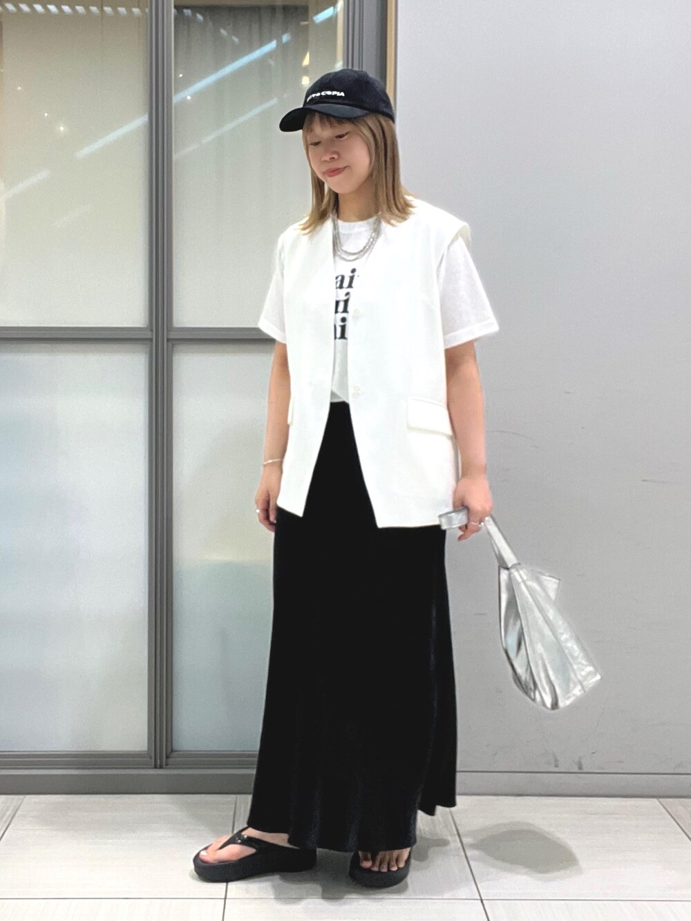 ホワイト系のベスト、ホワイト系のTシャツ/カットソー、ブラック系のスカートを着用したレディースの夏コーディネートの2枚目の写真