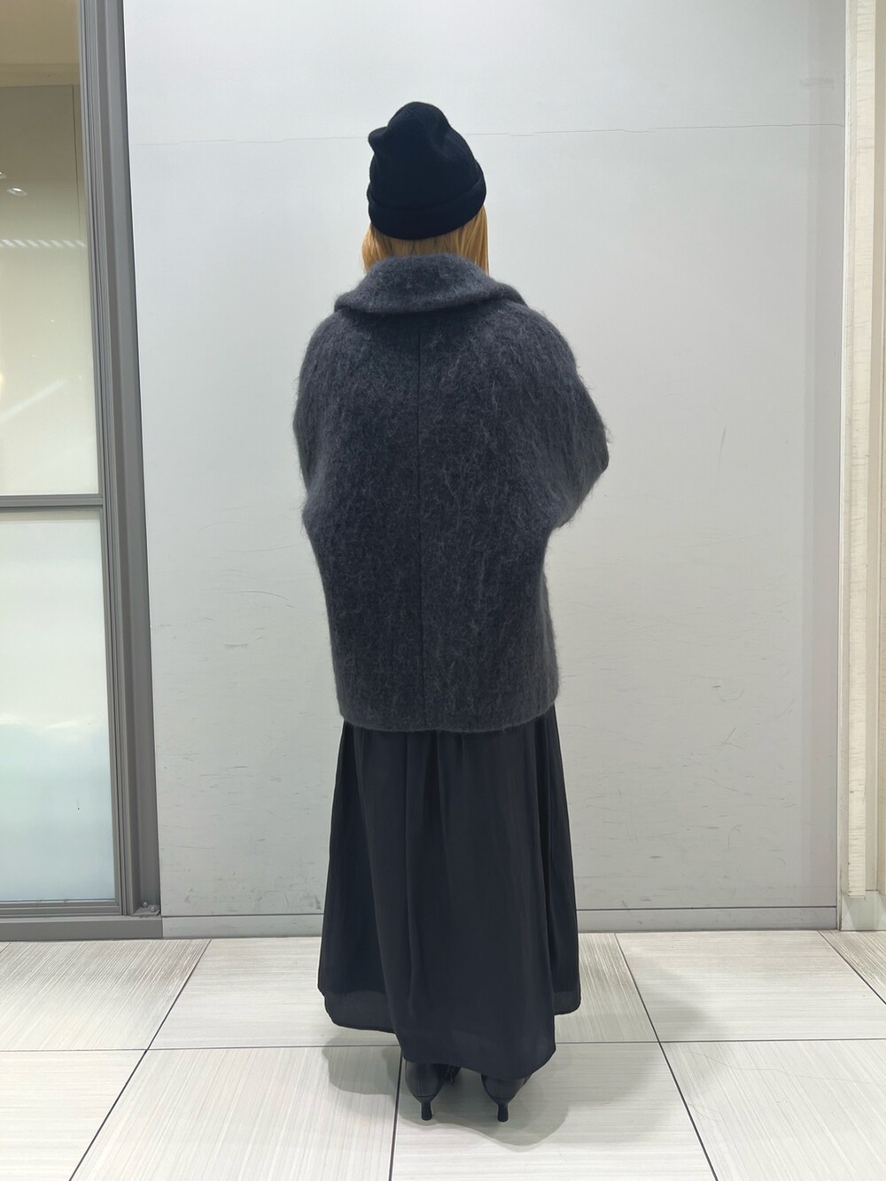 グレー系のピーコート、ブラック系のスカート、ブラック系のブーツを着用したレディースの秋コーディネートの6枚目の写真