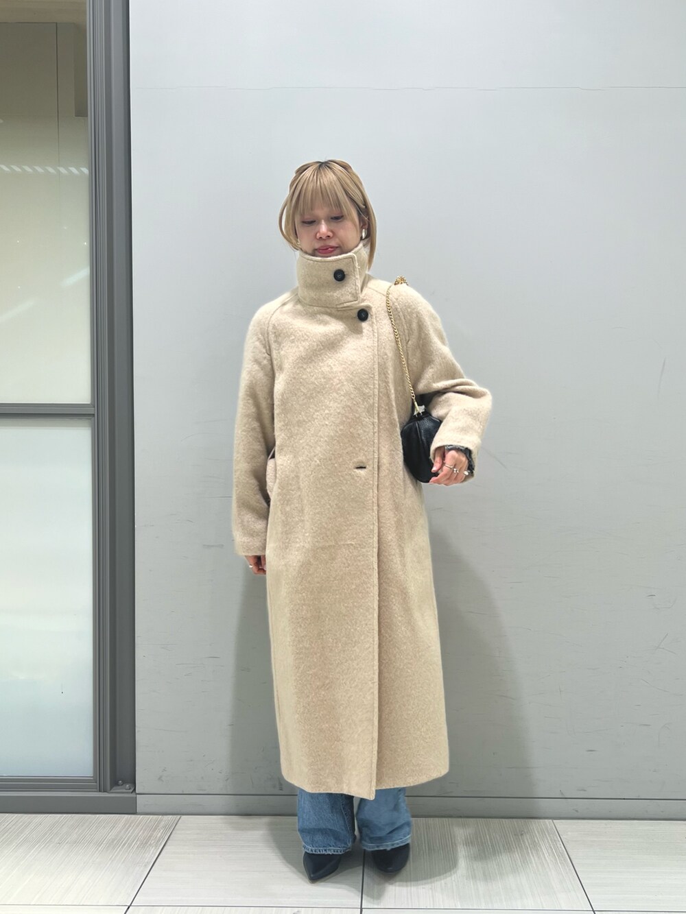 ブルー系のデニムパンツ、ブラウン系のワンピース、ベージュ系のその他アウターを着用したレディースの冬コーディネートの6枚目の写真