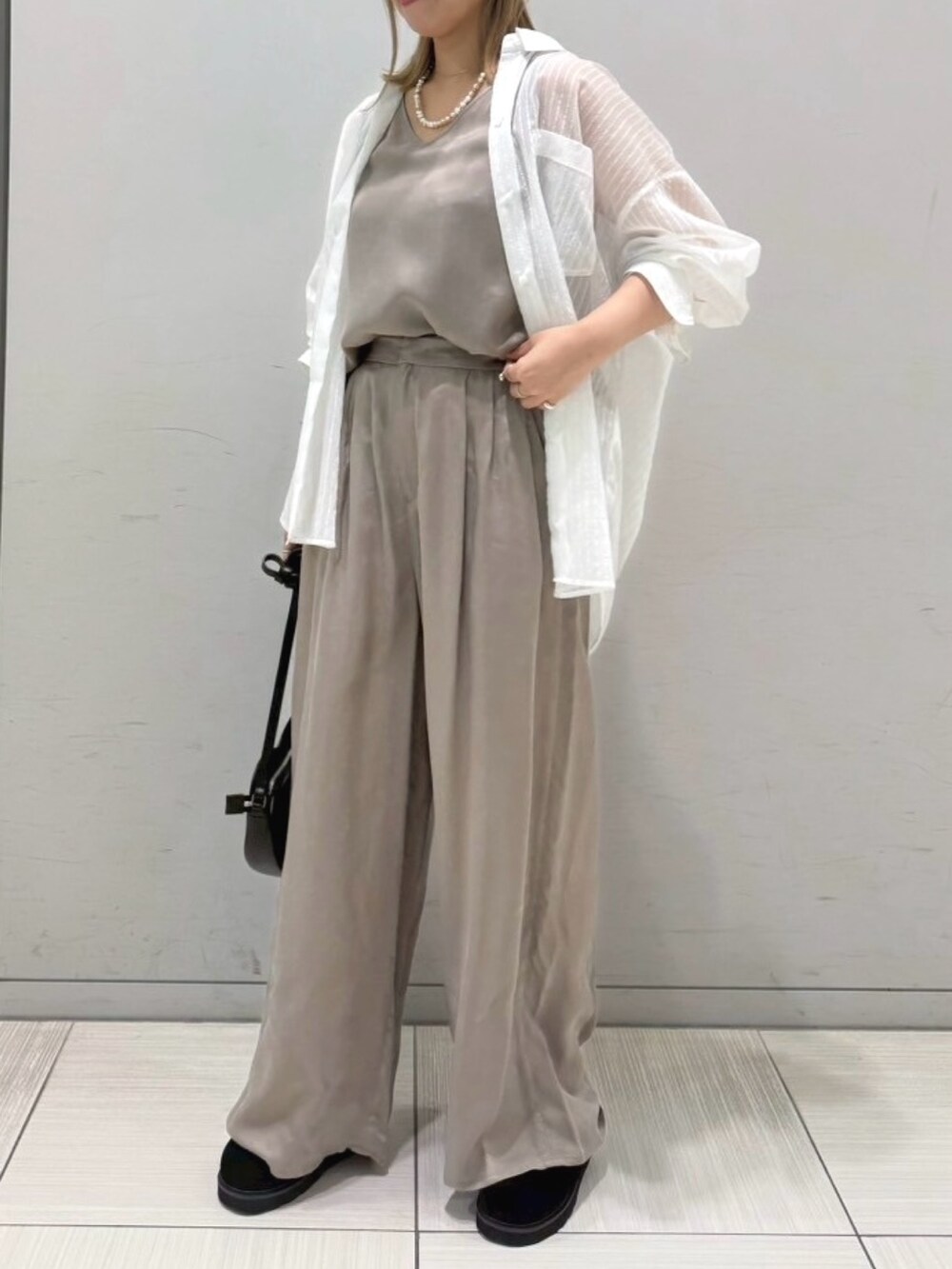 ブラック系のサンダル、ホワイト系のシャツ/ブラウス、ブラック系のショルダーバッグを着用したレディースの夏コーディネートの3枚目の写真