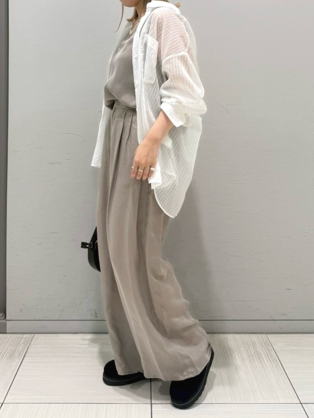 ブラック系のサンダル、ホワイト系のシャツ/ブラウス、ブラック系のショルダーバッグを着用したレディースの夏コーディネートの2枚目の写真