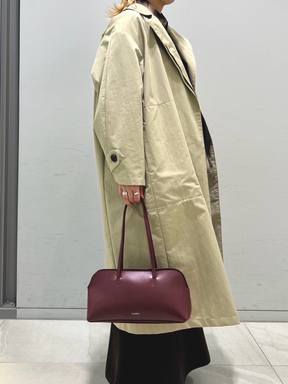 レッド系のショルダーバッグ、ブラウン系のシャツ/ブラウス、ベージュ系のステンカラーコートを着用したレディースの秋コーディネートの4枚目の写真