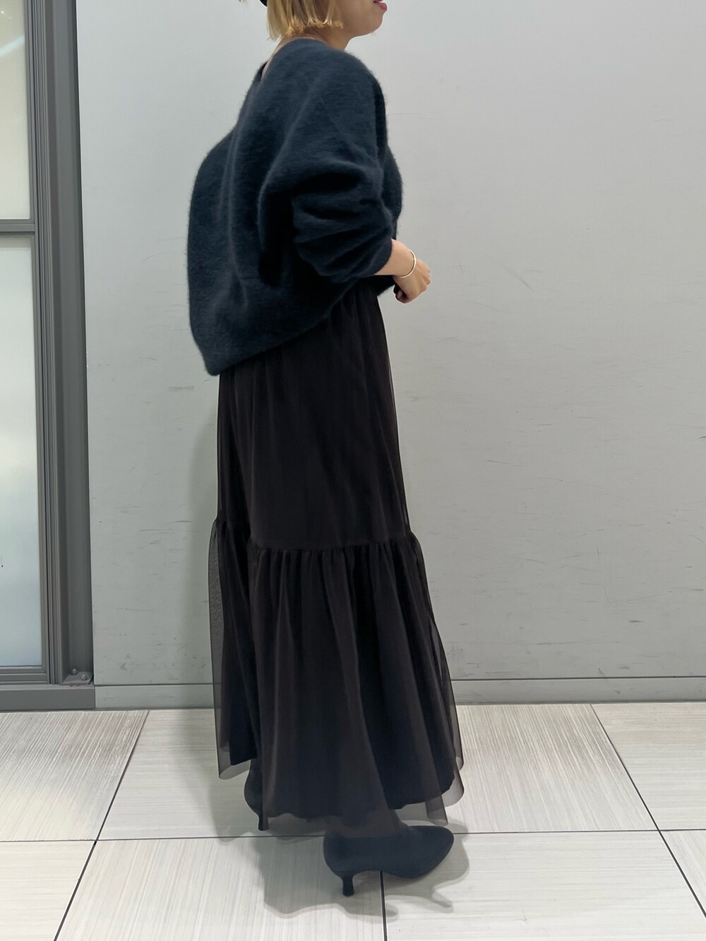 グレー系のニット/セーター、ブラウン系のスカート、ブラック系のブーツを着用したレディースの秋コーディネートの4枚目の写真