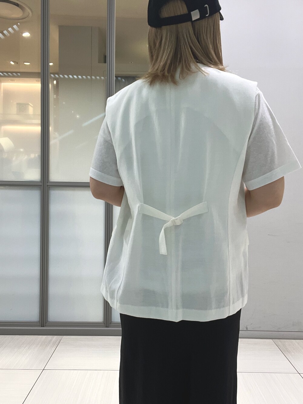 ホワイト系のベスト、ホワイト系のTシャツ/カットソー、ブラック系のスカートを着用したレディースの夏コーディネートの4枚目の写真