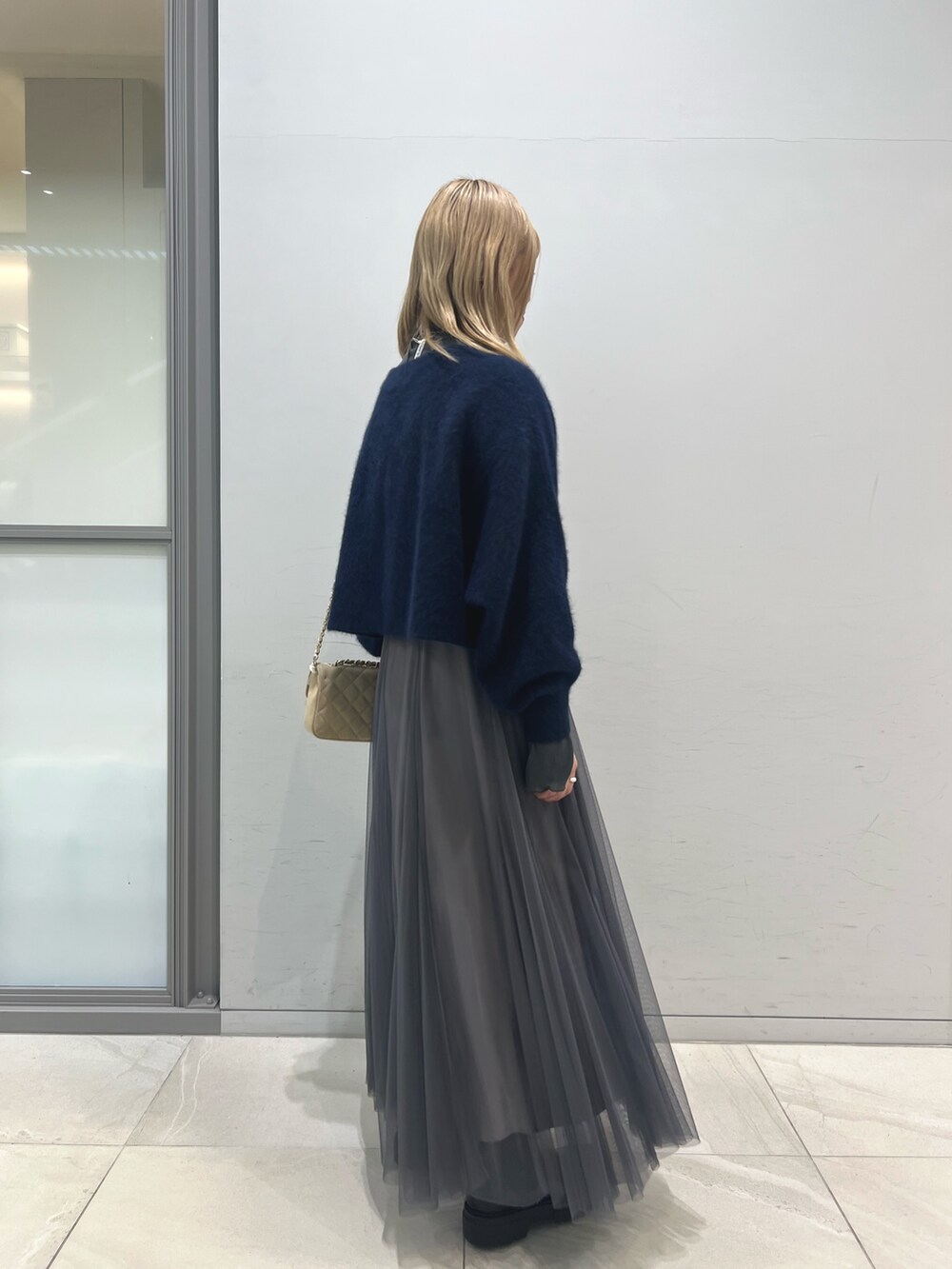 ブラック系のブーツ、グレー系のスカート、ベージュ系のショルダーバッグを着用したレディースの冬コーディネートの4枚目の写真