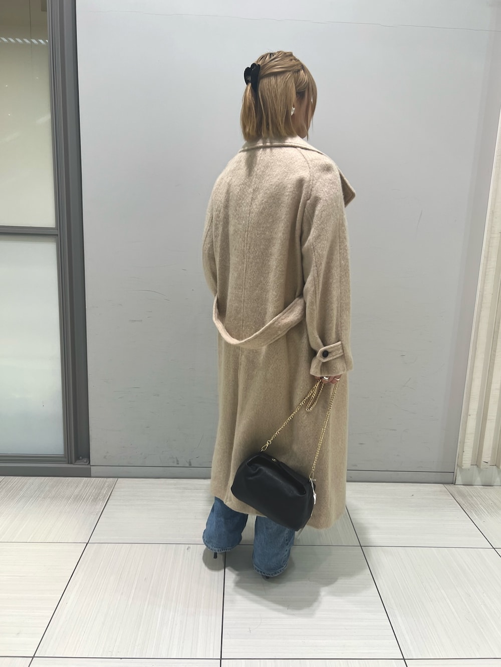 ブルー系のデニムパンツ、ブラウン系のワンピース、ベージュ系のその他アウターを着用したレディースの冬コーディネートの4枚目の写真