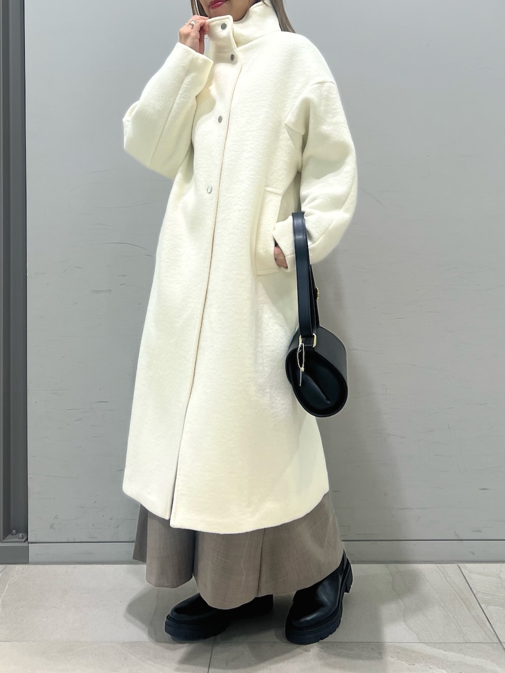 ブラック系のショルダーバッグ、ブラック系のブーツ、ホワイト系のその他アウターを着用したレディースの冬コーディネートの4枚目の写真