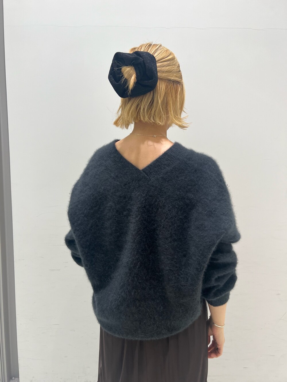 グレー系のニット/セーター、ブラウン系のスカート、ブラック系のブーツを着用したレディースの秋コーディネートの3枚目の写真