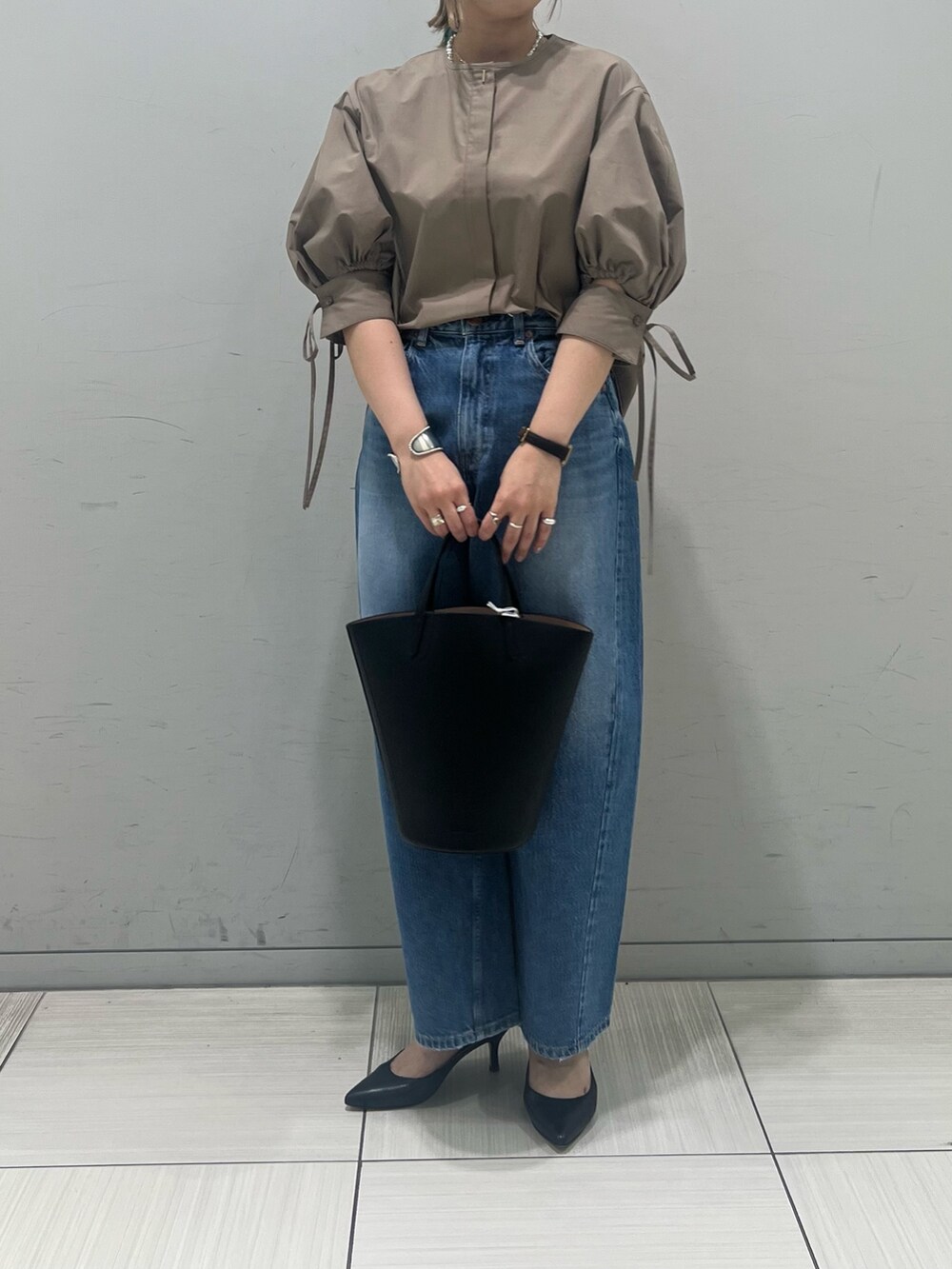 ブラウン系のシャツ/ブラウス、ブルー系のデニムパンツ、ブラック系のハンドバッグを着用したレディースの春コーディネートの3枚目の写真