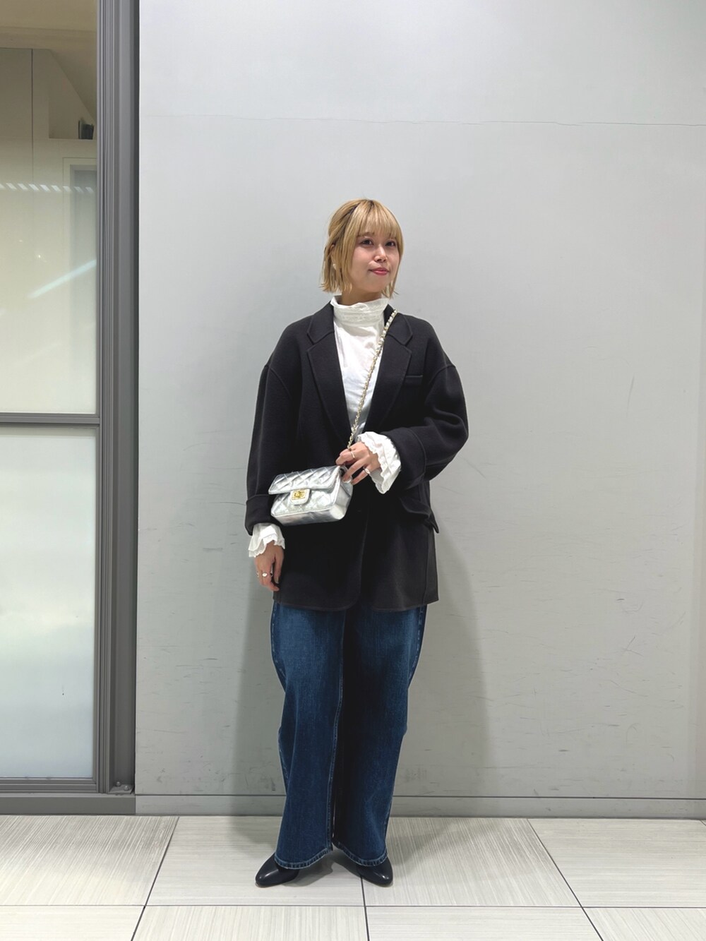 ブルー系のチェスターコート、ホワイト系のシャツ/ブラウス、ブルー系のデニムパンツを着用したレディースの秋コーディネートの3枚目の写真