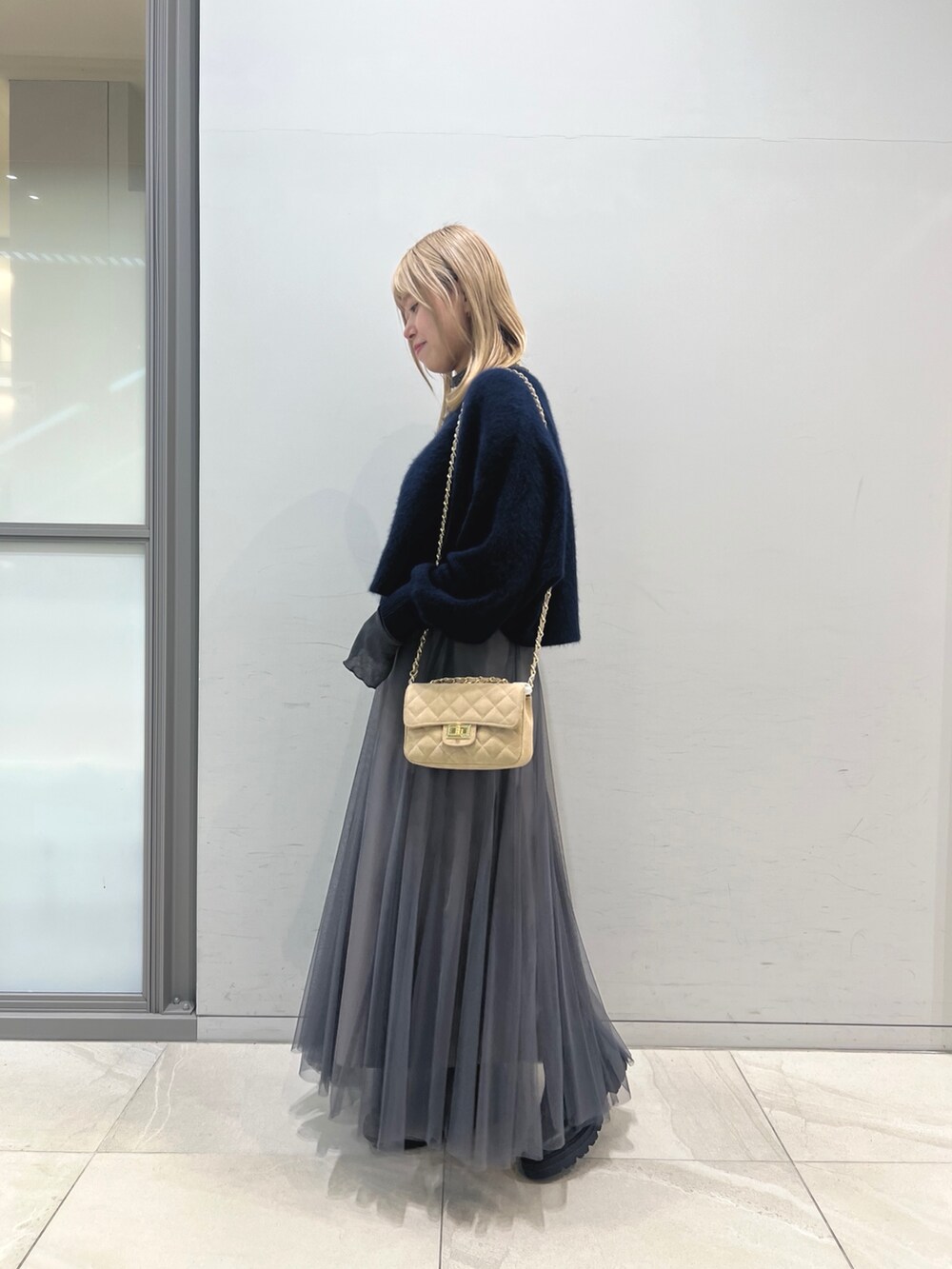 ブラック系のブーツ、グレー系のスカート、ベージュ系のショルダーバッグを着用したレディースの冬コーディネートの2枚目の写真