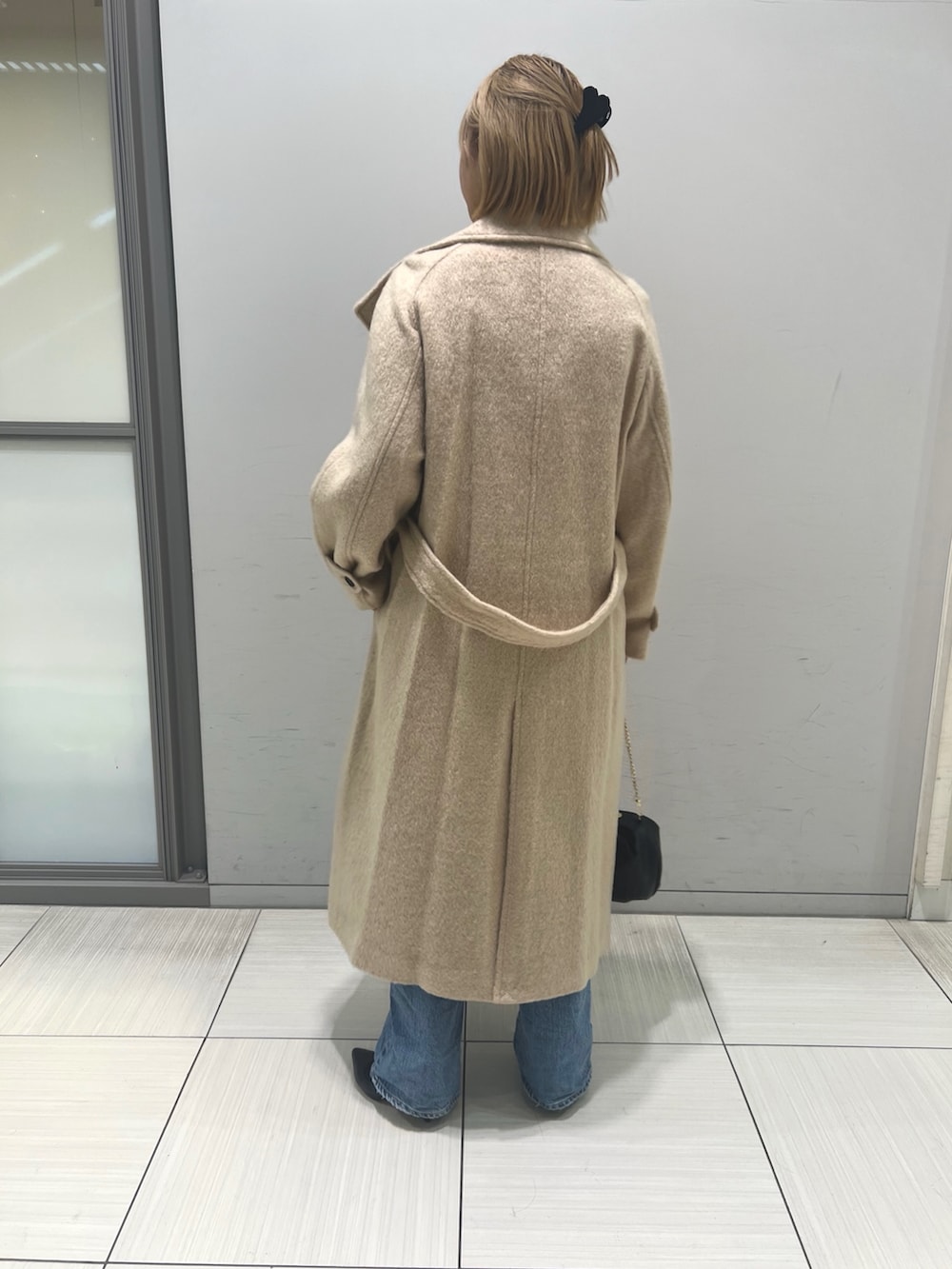 ブルー系のデニムパンツ、ブラウン系のワンピース、ベージュ系のその他アウターを着用したレディースの冬コーディネートの9枚目の写真