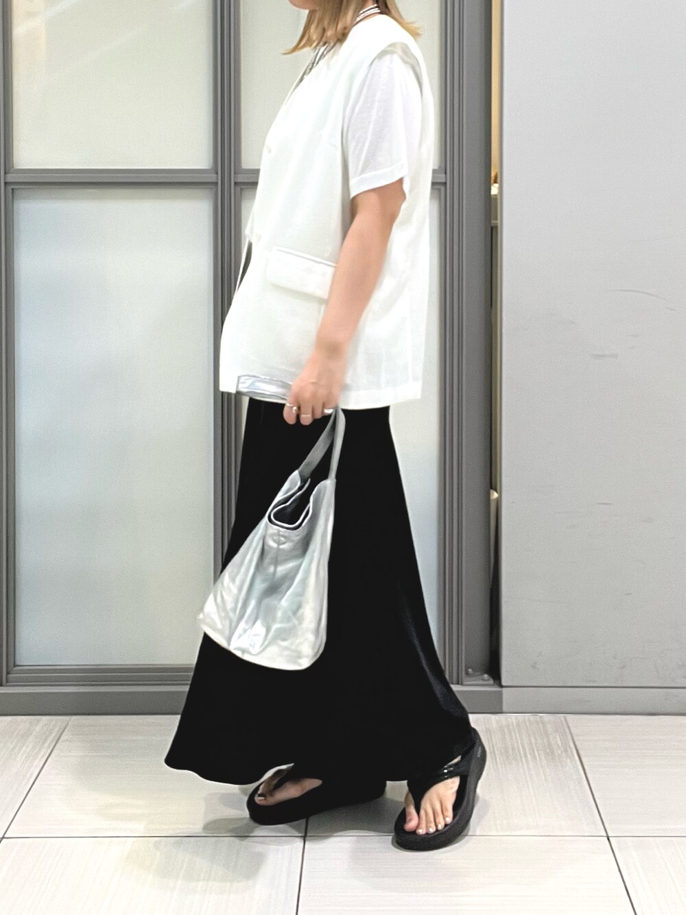 ホワイト系のベスト、ホワイト系のTシャツ/カットソー、ブラック系のスカートを着用したレディースの夏コーディネートの5枚目の写真