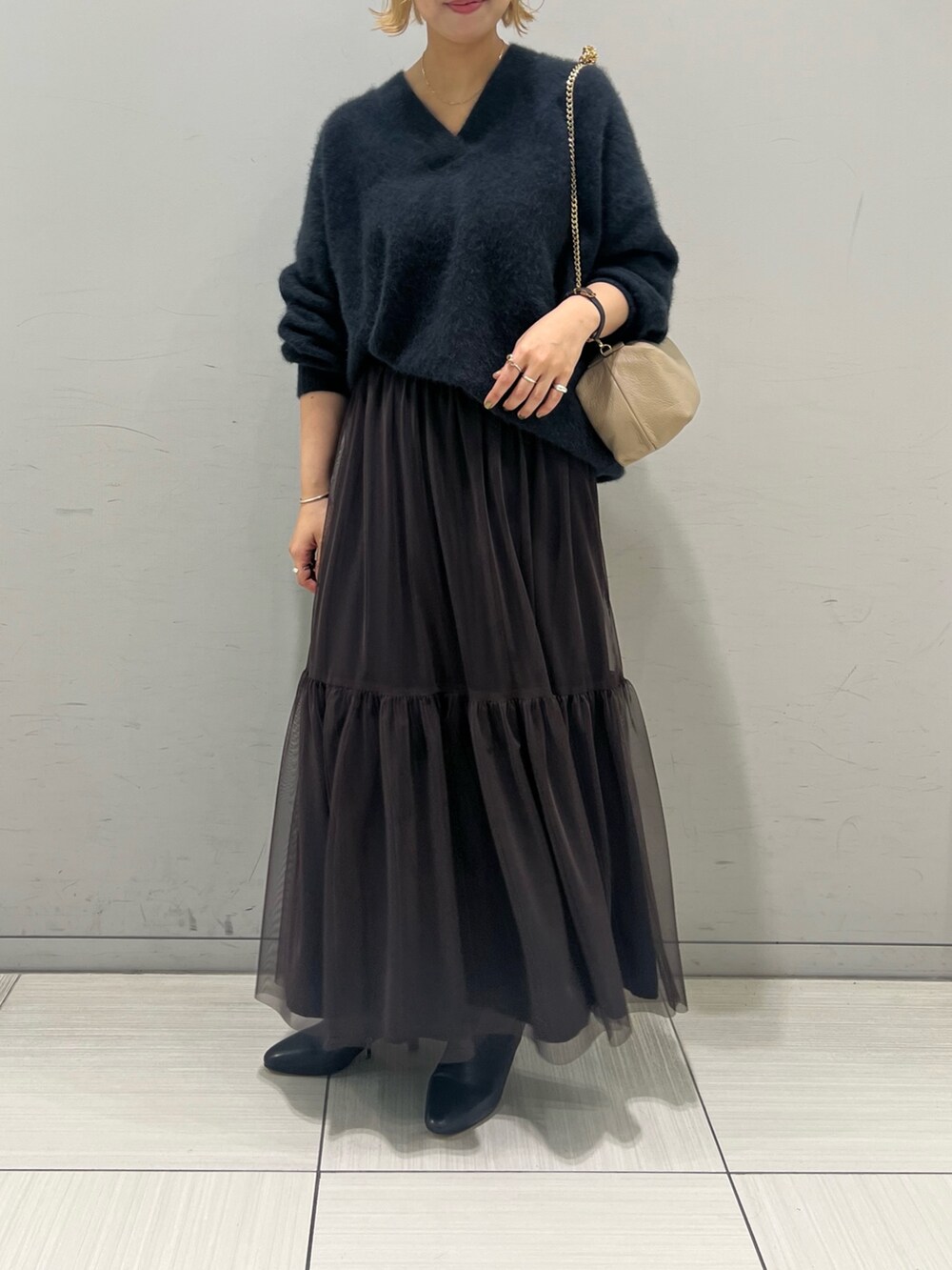 グレー系のニット/セーター、ブラウン系のスカート、ブラック系のブーツを着用したレディースの秋コーディネートの2枚目の写真