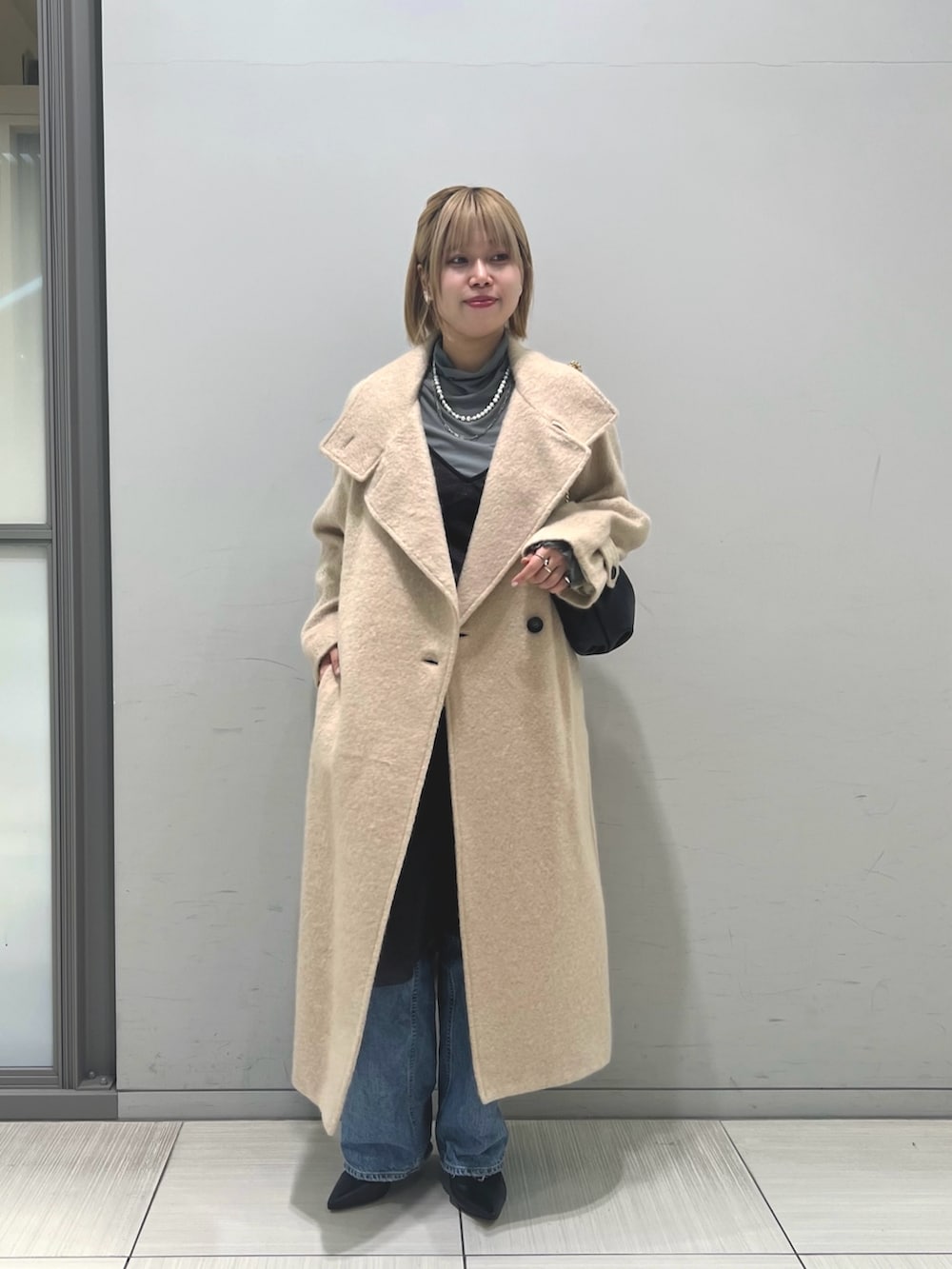 ブルー系のデニムパンツ、ブラウン系のワンピース、ベージュ系のその他アウターを着用したレディースの冬コーディネートの3枚目の写真