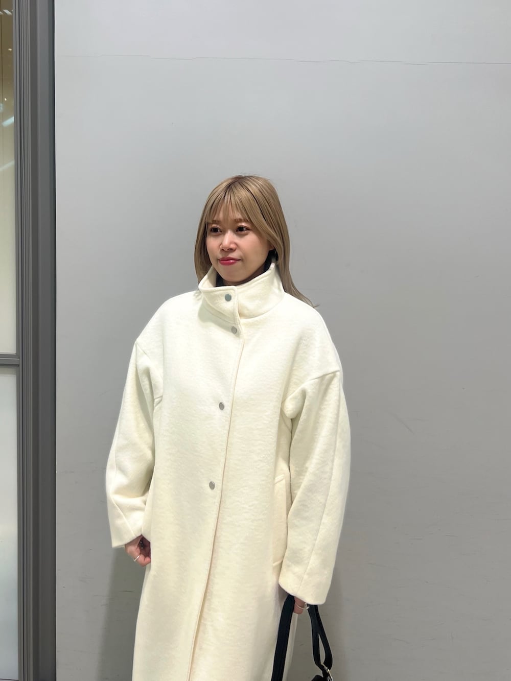 ブラック系のショルダーバッグ、ブラック系のブーツ、ホワイト系のその他アウターを着用したレディースの冬コーディネートの2枚目の写真