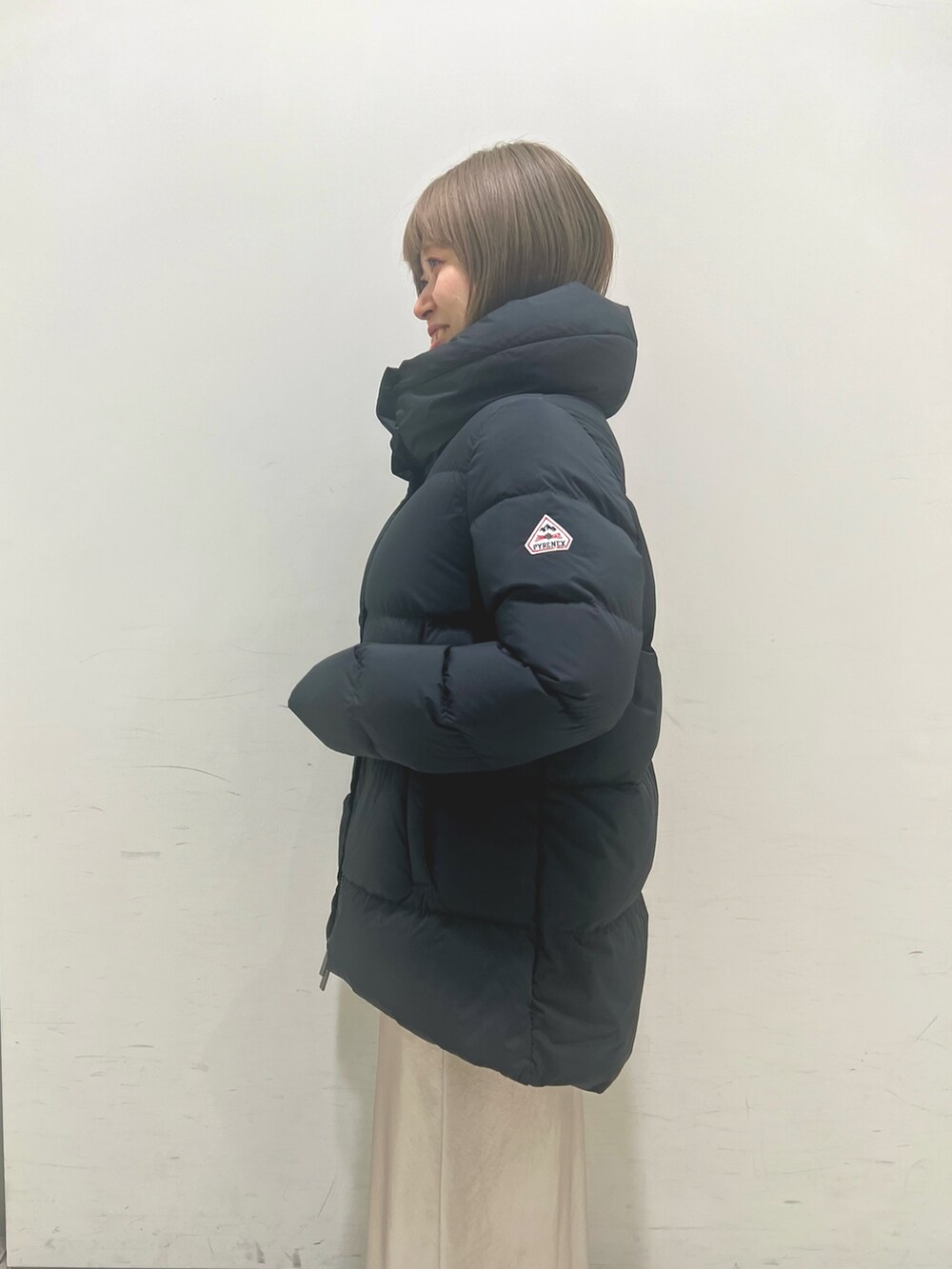 ブルー系のベスト、ベージュ系のスカート、ブラック系のダウンジャケット/コートを着用したレディースの秋コーディネートの4枚目の写真