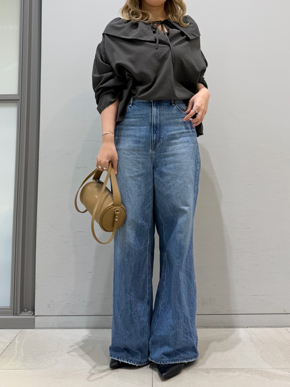 ブルー系のデニムパンツ、オレンジ系のショルダーバッグ、グレー系のシャツ/ブラウスを着用したレディースの春コーディネートの5枚目の写真