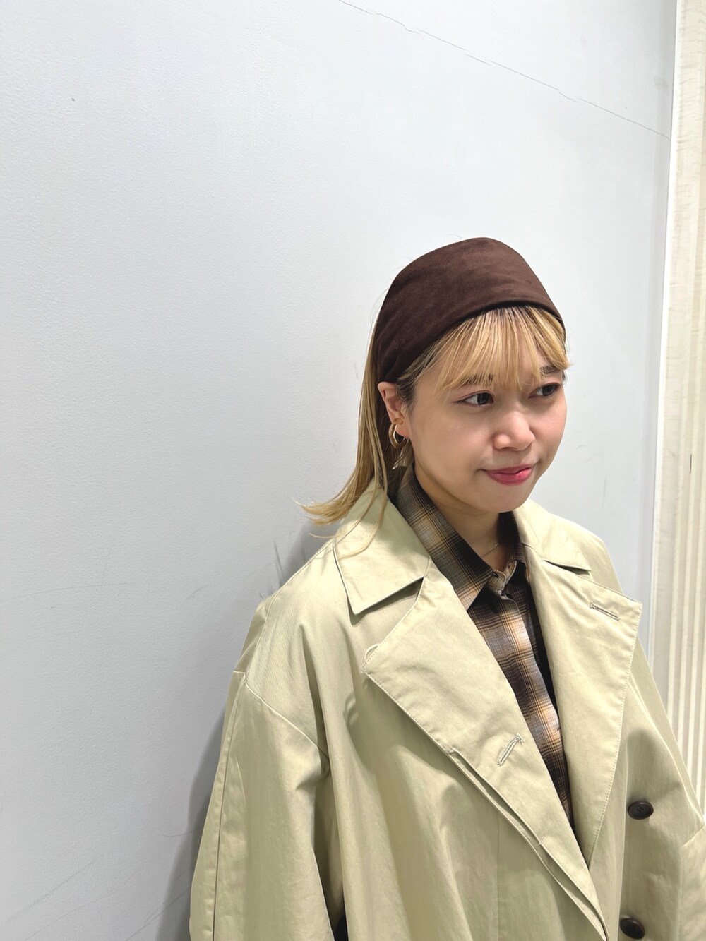 レッド系のショルダーバッグ、ブラウン系のシャツ/ブラウス、ベージュ系のステンカラーコートを着用したレディースの秋コーディネートの2枚目の写真